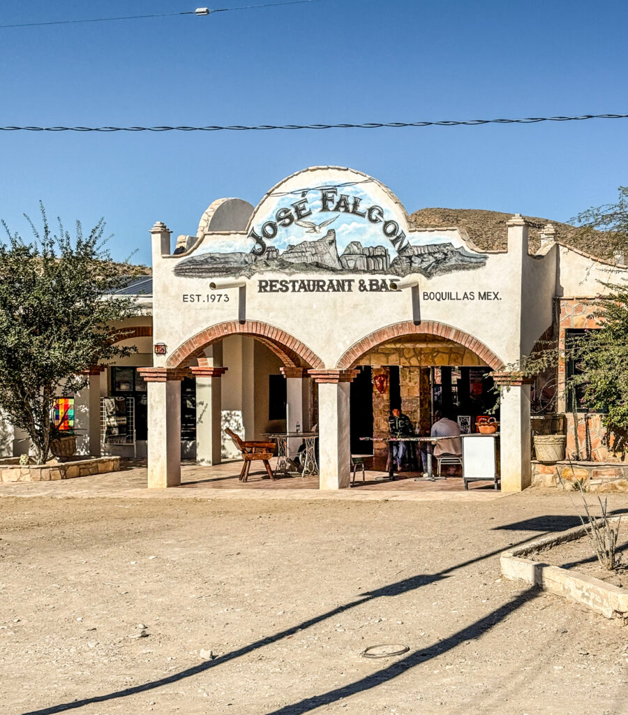 Exterior view of Jose Falcon Restaurant & Bar in Boquillas del Carmen, featuring a vibrant sign and a dusty landscape.